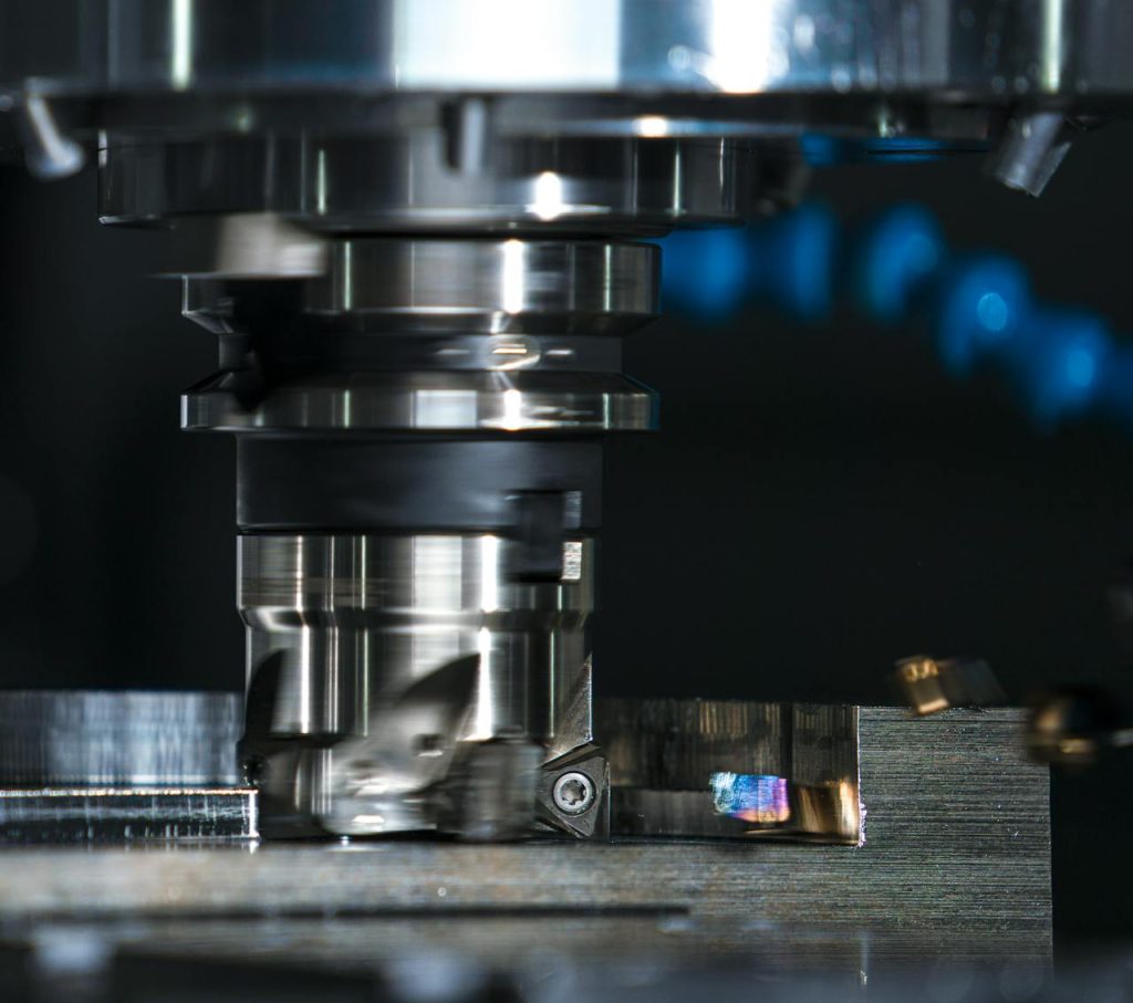 High-precision milling machine cutting a metal piece, showcasing industrial machinery.