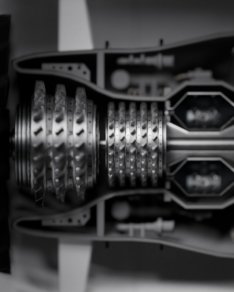 Internal turbine section presented in a straight-through cut, emphasizing the repetition and precision of compressor stages. The stacked blades form a tight mechanical rhythm, guiding the eye along the central axis while surrounding structures fade softly out of focus. It feels controlled and engineered, with every element aligned for function and flow.